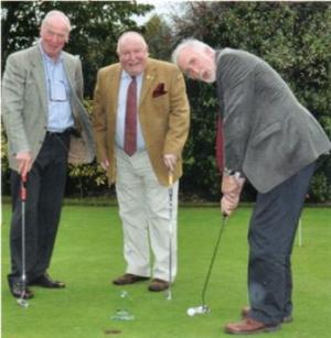 Gareth Davies practises his putting while John Bannon and Tim Reardon-Smith look on.